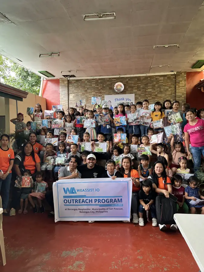 Reef Colman with children holding school kits at the WeAssist outreach program in Batangas