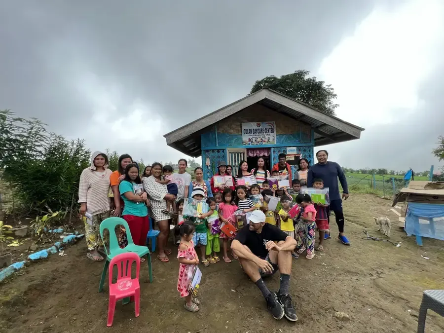 Reef Colman with families outside Culan Daycare Center after handing out school kits