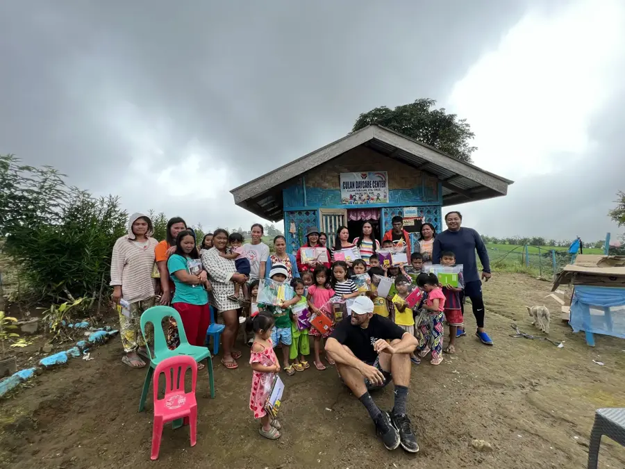 Reef Colman with families outside Culan Daycare Center after handing out school kits