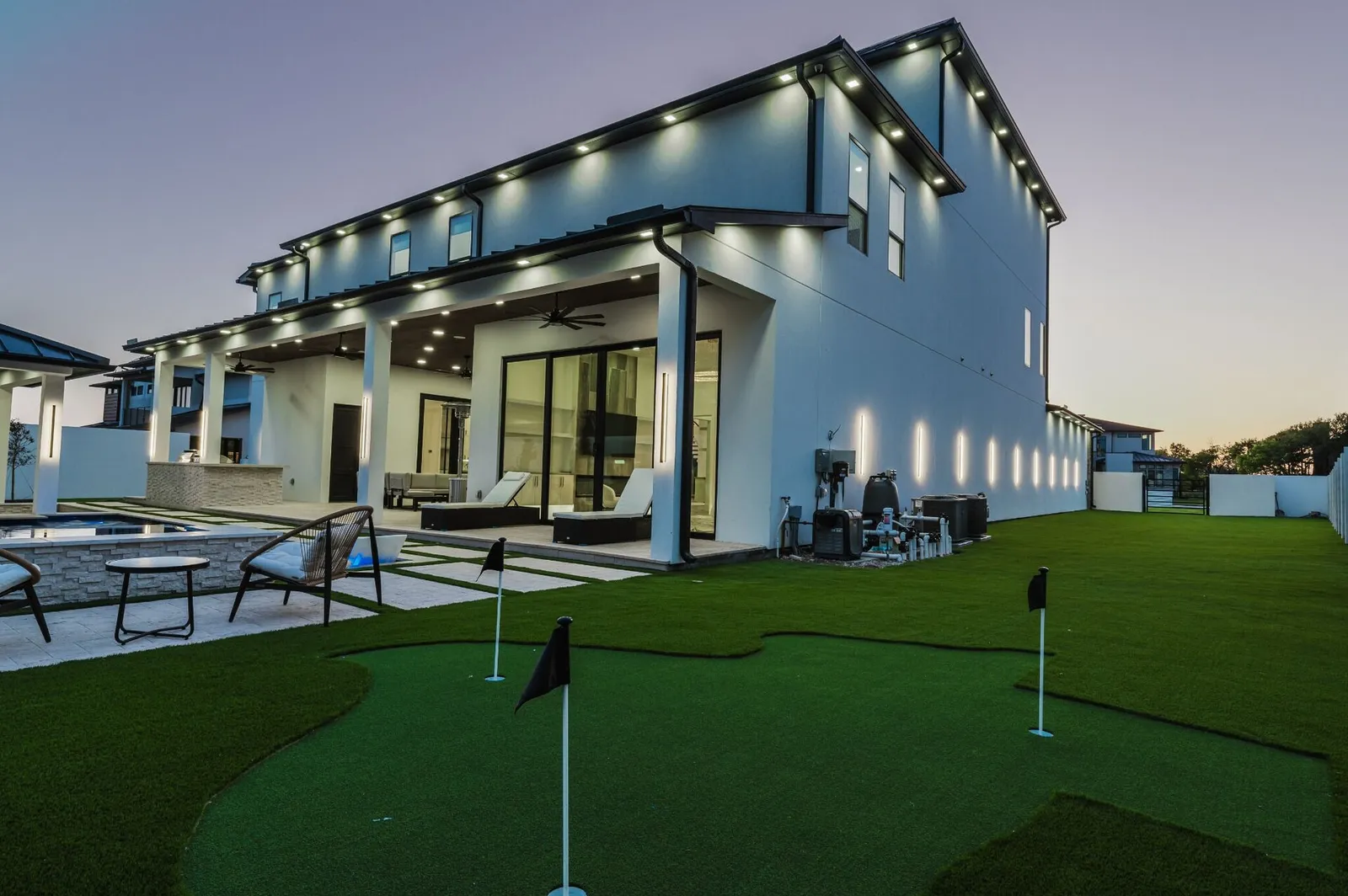 The covered patio at dusk, loungers and a putting green