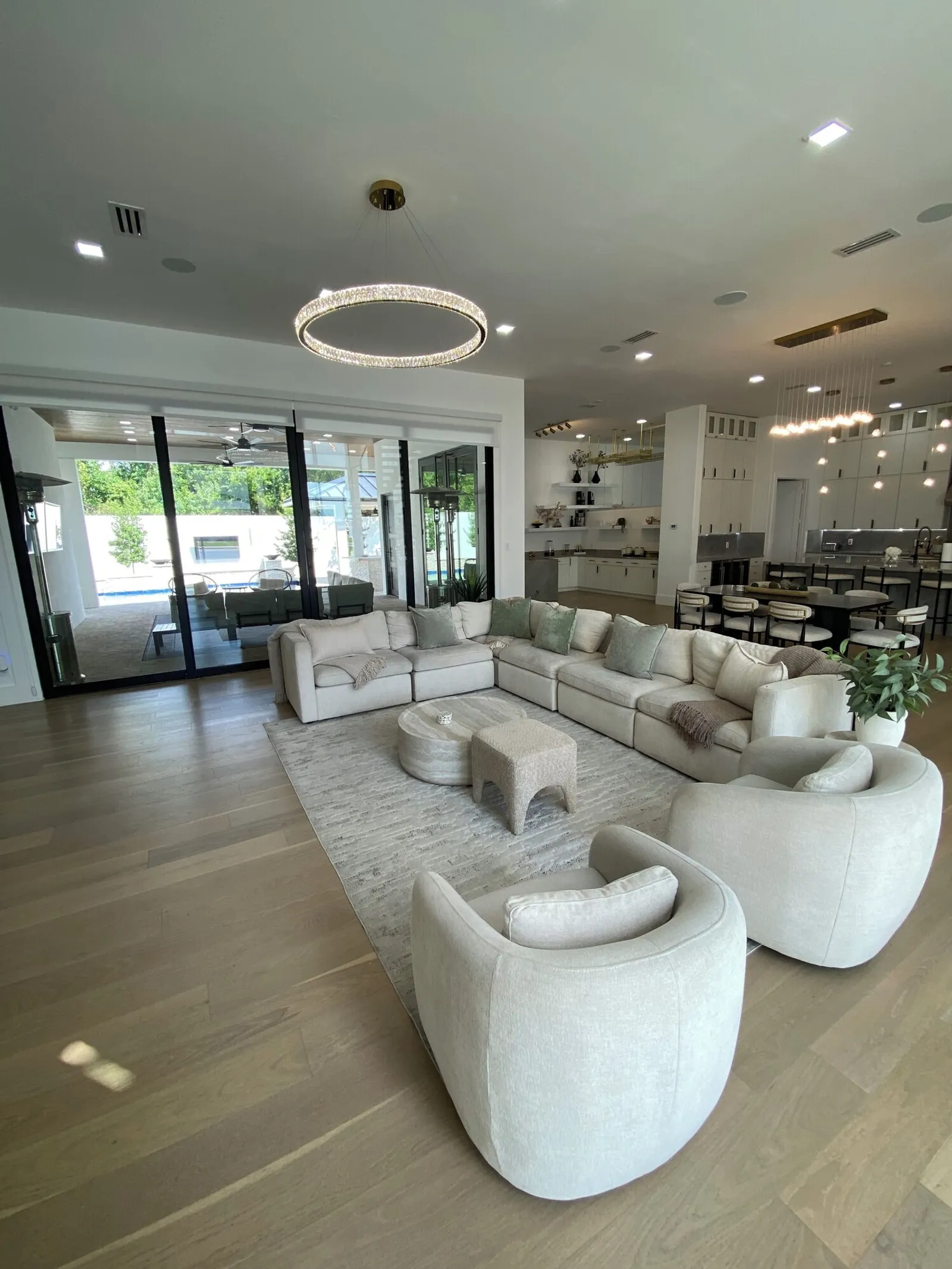 The salon: a sectional under a crystal ring chandelier, glass walls to the patio